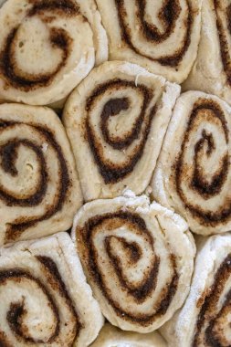 Mutfak masasında seramik bir tabakta pişirilmiş taze ev yapımı tarçın ruloları. Sıcak altın kabuk, sarmal doku, tatlı tatlı konsepti, sıcak ev yapımı atmosfer..