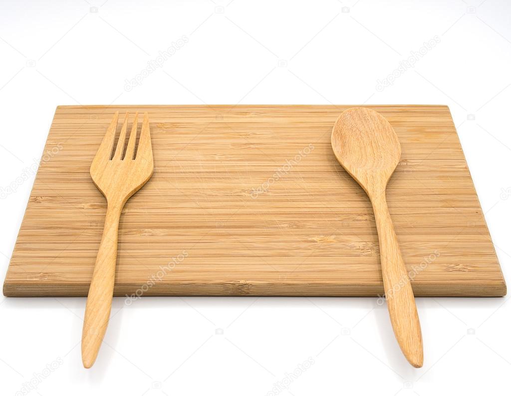 A wooden cutting board with wooden spoon and fork on the white b