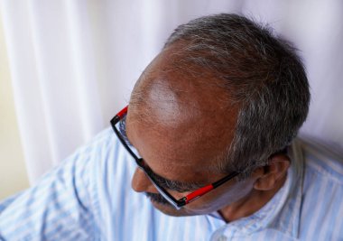 Beyaz arka planda saçlarını öne doğru gösteren yaşlı bir Hintli. Yakın çekim ve seçici odaklı çekim.