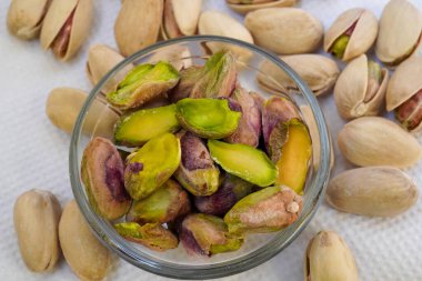 Cam bir kaseye tuzlu şam fıstığı serpiştirilmiş ve beyaz arka planda, yalıtılmış, yan görüş, kızarmış fındık, lezzetli, besleyici aperatif, sağlıklı organik gıda, yüksek proteinli.