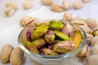 Cam bir kaseye tuzlu şam fıstığı serpiştirilmiş ve beyaz arka planda, yalıtılmış, yan görüş, kızarmış fındık, lezzetli, besleyici aperatif, sağlıklı organik gıda, yüksek proteinli