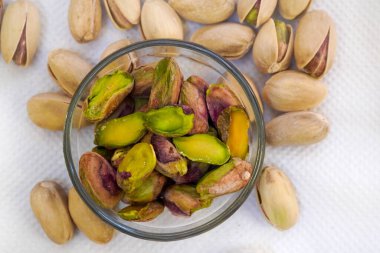 Cam bir kaseye tuzlu şam fıstığı serpiştirilmiş ve beyaz arka planda, yalıtılmış, yan görüş, kızarmış fındık, lezzetli, besleyici aperatif, sağlıklı organik gıda, yüksek proteinli