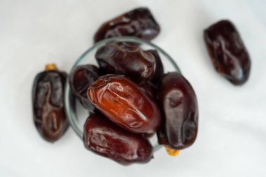 Beyaz arka planda cam kasede kurutulmuş hurmalar. Tatlı, besleyici ve lif açısından zengin olan hurma, atıştırmalıklar, tatlılar ve sağlıklı beslenme için popüler bir meyvedir..