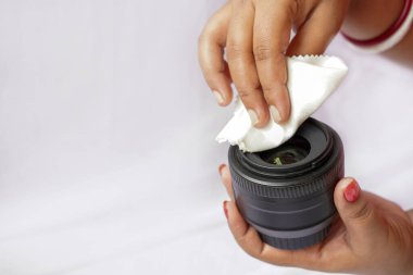 Beyaz arkaplanda izole edilmiş beyaz temizlik beziyle dijital kamera lenslerini temizleyen eller.