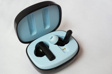 Temassız şarjlı kablosuz siyah kulaklıklar beyaz arka planda izole edilmiş. Seçici odaklanma. Kablosuz müzik konseptini dinle.