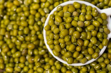 Organik yeşil Gram 'ın (Vigna radyatör) makro yakın çekimi ya da beyaz seramik çorba kaşığı üzerinde yeşil moong dalının tamamı. Üst görünüm, kendi gradyan arkaplanı üzerinde.
