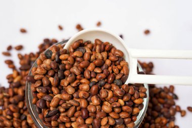 Beyaz arka planda izole edilmiş beyaz kaşıkta at gramı. Kulthi dal veya at gramı safra kesesi taşı, böbrek taşı ve böbrek sağlığını korumak gibi iyileştirici özellikleriyle yaygın olarak bilinir..