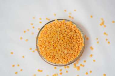 Organik sarı Gram 'a (Vigna radyatör) yakın durun ya da sarı moong dalına bölünmüş sarı moong dalının eğimli arka planına sahip seramik beyaz bir kasede sarı moong dalını ayırın. Üst görünüm