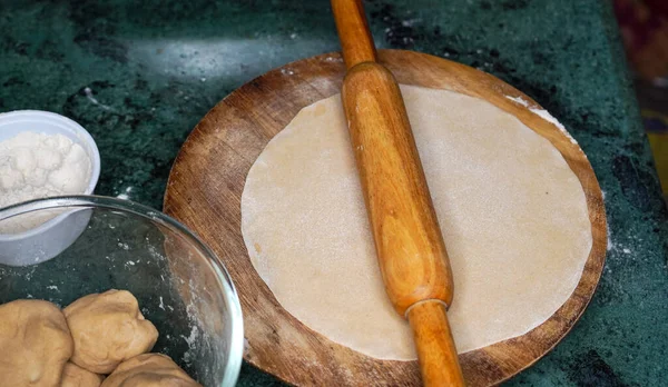 Hamur hazırlığı. Hamuru yuvarlanmış bir un tokasıyla. Beyaz ahşap bir arka planda. Üst görünüm.