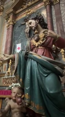 İtalya, Parma, Sant 'Ambrogio Kilisesi, 17 Ekim 2025. İtalya' daki süslü bir barok kilisesindeki aziz heykeli ve melek figürünün ayrıntılarını gösteren bir video. Yazar: Djundiet A.