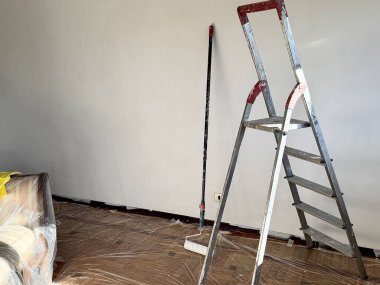 İtalya, Borgo San Dalmazzo. 11 Aralık 2025 İçişleri odası merdiven ve boya silindiriyle boyamaya hazır. Ev yenileme işlemi sırasında zemin plastik kaplamayla korunuyor. Yazar: Djundiet A.