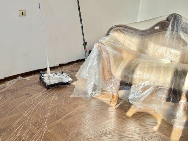 Italy, Borgo San Dalmazzo. December 11, 2025Interior of a home prepared for renovation. Furniture is covered with plastic, and painting tools and materials are set on the floor.Author: Djundiet A.