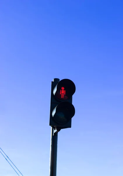 Açık mavi gökyüzüne, şehir güvenliğine ve bekleme konseptine parlayan kırmızı yaya trafik ışığı