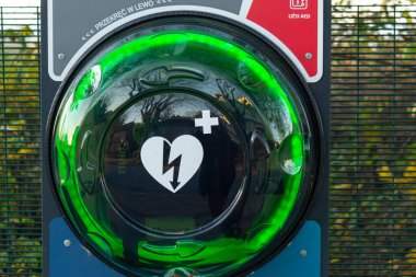 Halka açık bir dış defibrilatör AED 'nin yakın plan fotoğrafı. Parlayan yeşil kalp sembolü ve şimşekle Polonya' da acil kardiyak kurtarma için yerleştirilmiş.