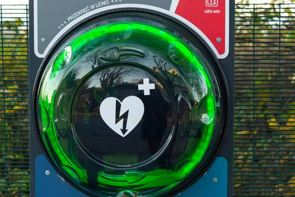 Halka açık bir dış defibrilatör AED 'nin yakın plan fotoğrafı. Parlayan yeşil kalp sembolü ve şimşekle Polonya' da acil kardiyak kurtarma için yerleştirilmiş.