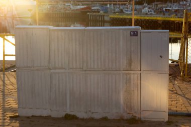 Ustka limanındaki yıpranmış metal bir nakliye konteynır kapısının paslı asma kilidine yakın çekim. Gün batımında parlıyor. Güvenlik, depolama, deniz koruma ve endüstriyel güvenilirliği çağrıştırır