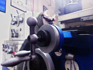 Mühendislik atölyesindeki metal torna tezgahının kontrol kolunu kapat. Sapının dokulu detaylarına ve ölçüm ölçeğine odaklan