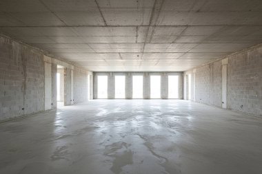 Bu iç mekan inşaat halinde. Ham beton zemin ve duvarları var. Camlardan içeri doğal ışık akıyor.