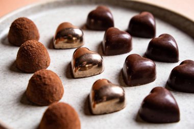 Çeşitli zanaatkar çikolatalarla dolu bir tabağın yakından görüntüsü, farklı dokular sergileniyor ve enfes bir ikram için bitiriliyor.