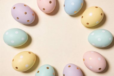 Beyaz ve altın benekli Paskalya yumurtalarının bir koleksiyonu yumuşak krem yüzeyinde dairesel bir desen içinde ustalıkla düzenlenmiştir.
