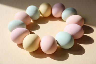 Zarif renklerde Paskalya yumurtalarının bir araya getirilmesi dairesel bir şekil oluşturur. Yumuşak güneş ışığıyla yıkanır ve ince gölgeler yaratır.