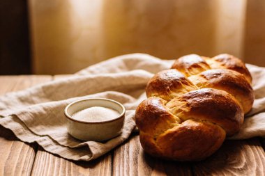 Taze pişmiş, altın sarısı, güzel örgülü bir somun, keten bir bezin üzerinde, granülatif şekerden oluşan küçük bir tabağın yanında oturur.