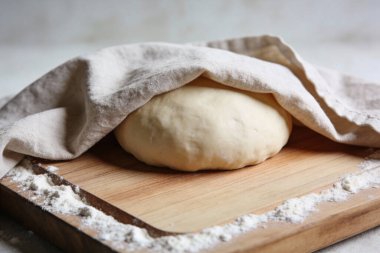 Çiğ hamurdan bir top açık renkli keten kumaşla kaplıdır. Tahta kesme tahtasına konur. Un ile kaplıdır.