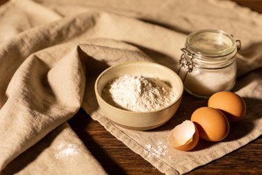 Bir kase un, yumurta ve şekerin pişirilmeye hazır olduğu durgun bir yaşam kompozisyonu.