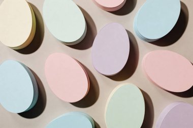 Çeşitli yumuşak pastel renklerdeki yumurta şekilli kağıt kesiklerinin bir koleksiyonu görsel olarak çekici bir Paskalya temalı kompozisyon yaratır.
