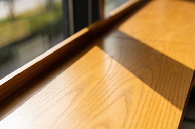 A close-up view of a polished wooden surface bathed in natural sunlight, revealing intricate wood grain textures and casting soft shadows