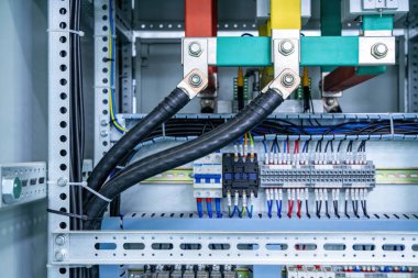 Ağır kablolar, devre kesiciler ve güç yönetimi için terminal bloklarının yer aldığı modern bir elektrik dağıtım panosunun ayrıntılı görüntüsü