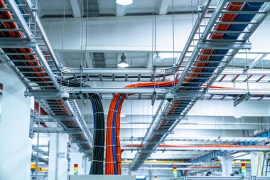 Kablolardan oluşan karmaşık bir ağ düzgünce elektrik kablolarını ve veri kablolarını büyük bir endüstriyel bina boyunca düzgünce yönlendirir.