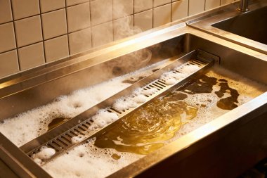 Paslanmaz çelik lavabo sıcak, sabunlu suyla doludur, buhar ve kabarcıklar yaratır.