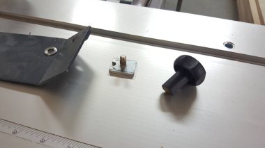 Siyah plastik bir düğme ve başlıklı bir metal deste bir cetvelin yanındaki tezgahta oturur.