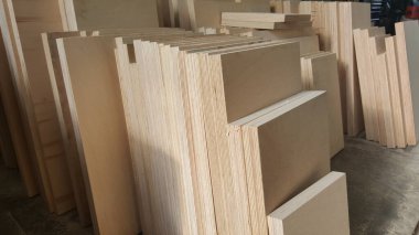 Kontrplak ve MDF panelleri de dahil olmak üzere büyük bir ham ahşap koleksiyonu, düzgün istiflenmiş ve inşaat veya mobilya yapımında kullanılmaya hazır.