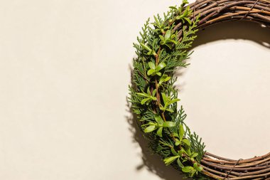 Dallardan yapılmış ve canlı yeşil yapraklar ve tomurcuklanan dallarla süslenmiş kırsal bir çelenk, yumuşak bir gölge oluşturur.