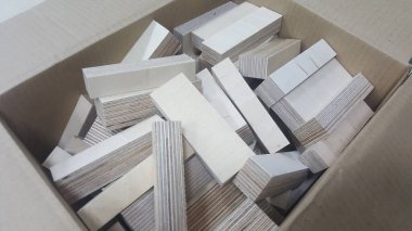 Sıradan bir karton konteynırın içinde rastgele istiflenmiş sayısız küçük, dikdörtgen ahşap parçadan oluşan yakın çekim görüntüsü, DIY veya imalat için hammadde öneriyor.