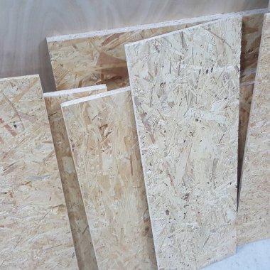 Birbirlerine yaslanmış birkaç OSB panelinin yakın görüntüsü, desenli yüzey ve ahşap yonga bileşimlerini sergiliyor