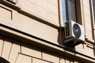 Açık hava havalandırma ünitesi açık kahverengi bir binanın kenarına eklenmiştir.