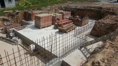 İnşaat malzemeleri ve kazılarla çevrili beton döşeme ve çelik inşaat demiri şebekesiyle yeni bir temel hazırlanıyor