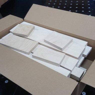 Uncut wooden planks and squares are stacked and organized within a brown shipping container, ready for transport or further processing