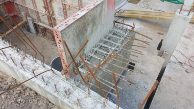Güçlendirilmiş beton yapı devam ediyor, beton çubuklara gömülü ve inşaat alanındaki formsal panelleri çevreleyen çelik çubukları gösteriyor