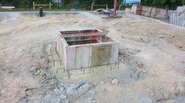 Çelik parmaklıkları güçlendiren beton bir yapı, inşaat sahasındaki yeni bir yapı için hazırlanıyor.