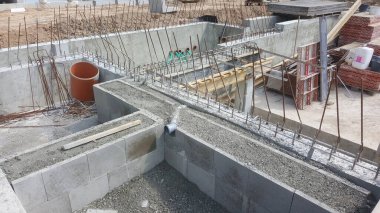 İnşaat halindeki bir binanın ayrıntılı görüntüsü, beton bloklar, çelik takviye çubukları ve boruların kurulumu