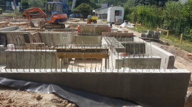 Beton duvarlar ve çelik takviye çubuklarıyla yeni bir yapı inşa edilirken, kazıcılar ve diğer ekipmanlar sahada görülebiliyor