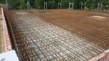 İnşaat halindeki bir binanın detaylı bir görüntüsü, beton dökülmeden önce yerleştirilmiş karmaşık çelik destek çubukları ağını gözler önüne seriyor.