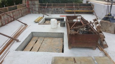 İnşaat alanı inşaatın bir sonraki aşaması için inşaat demirleri, formaliteleri ve malzemelerle dolu yeni dökülmüş beton bir levha gösteriyor.