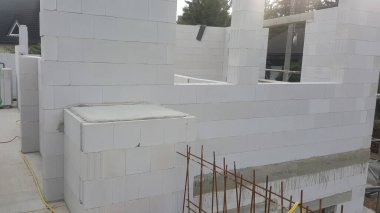 İnşaat halindeki bir binanın dış görünüşü, hafif beton blokların montajını ve yapısal takviyeyi gösteriyor