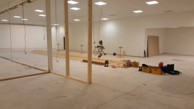 Tamamlanmamış ahşap duvarlar ve yere saçılmış inşaat malzemelerinin yer aldığı boş bir ticari alan.