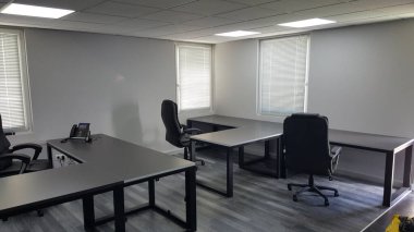 Pürüzsüz çalışma istasyonları, rahat koltuklar ve Venedik panjurlarından bol miktarda doğal ışık içeren çağdaş bir ofis.